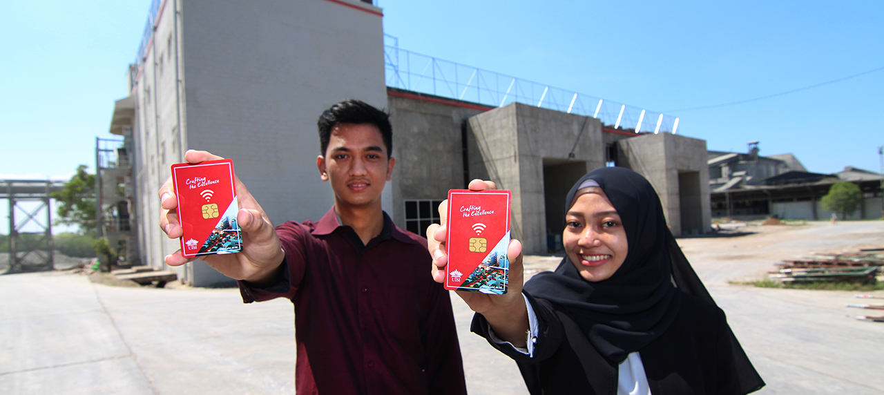 Mahasiswa memegang smart card di depan bangunan kampus