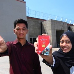 Mahasiswa memegang smart card di depan bangunan kampus Mahasiswa memegang smart card di depan bangunan kampus